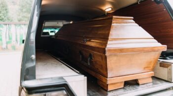 Saiba mais sobre o traslado funerário terrestre e tire suas dúvidas. Interior de um carro de transporte com caixão de madeira, ilustrando o traslado funerário terrestre.