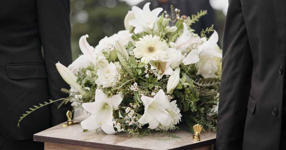 Arranjo de flores sobre urna em cerimônia representa que traslado funerário é seguro.